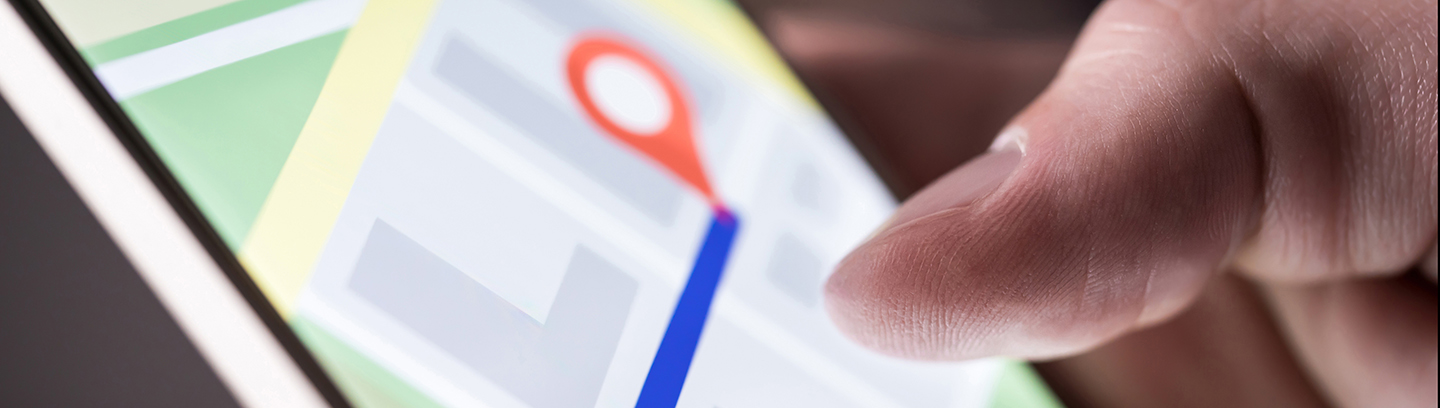 Image of a person's thumb and a smart phone showing directions on a map