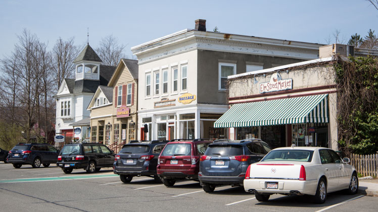 Photo of small business storefronts with cars parked in front.