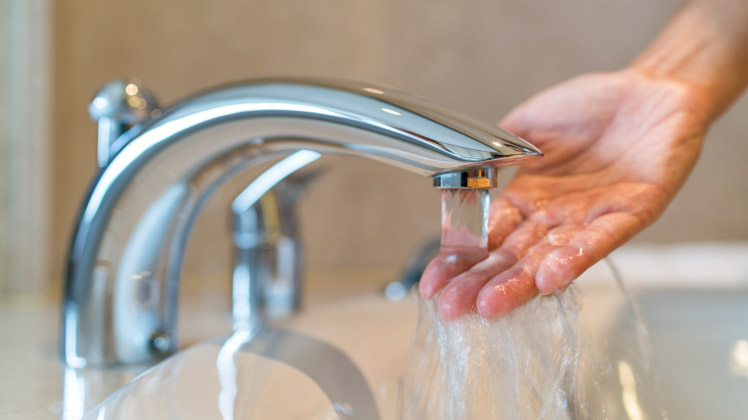 photo of hand under running water from bathtub faucet